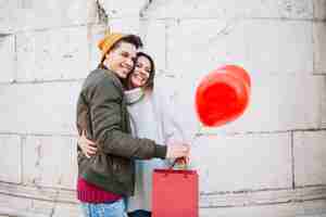 Foto gratuita coppia con palloncino e sacco di carta che abbraccia