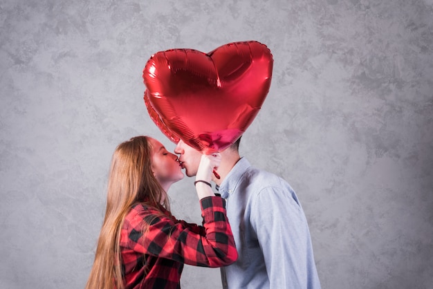 Couple with balloons in heart shape kissing 