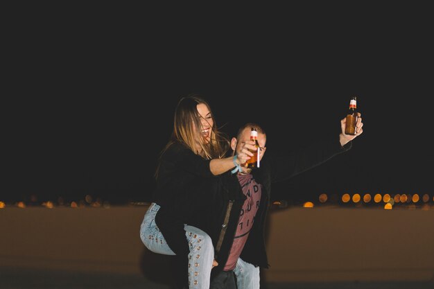 Couple with beer having fun on roof