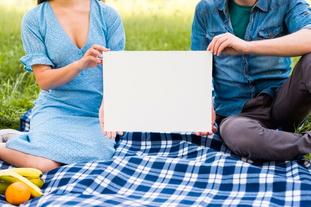 Couple with blank paper sitting on blanket
