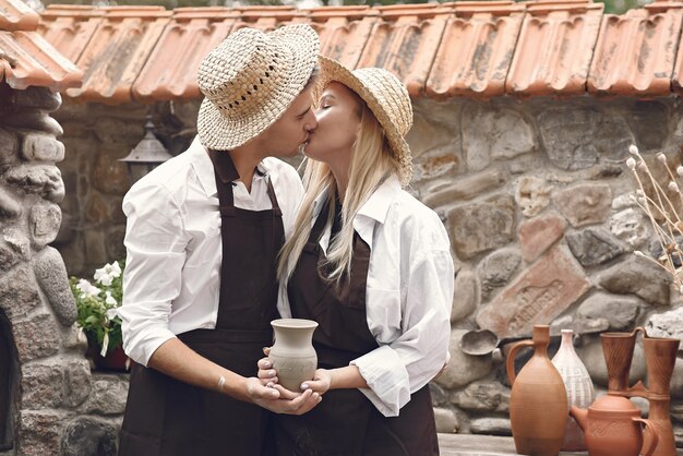 Couple with brown aprons and holding a vase