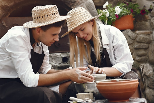 Couple with brown aprons making a vase