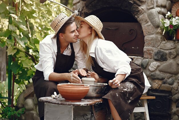 Couple with brown aprons making a vase