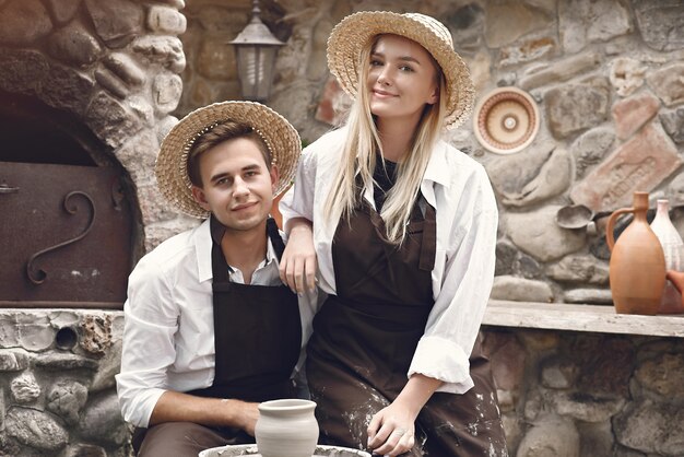 Couple with brown aprons making a vase