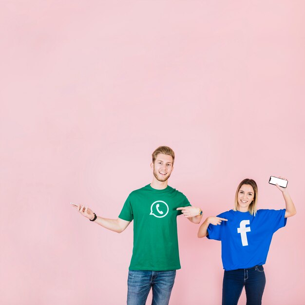 Couple with cellphone pointing at their t-shirt with facebook and whatsapp icon