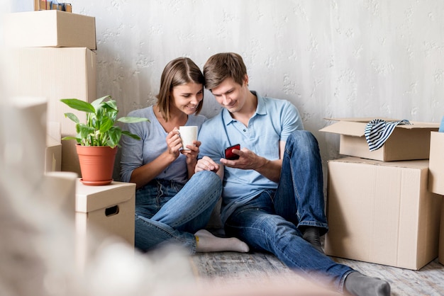 Couple with coffee and smartphone while packing to move house