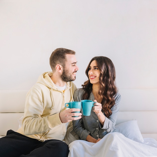 Couple with cups on bed