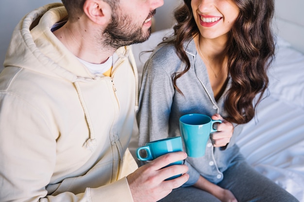 Free photo couple with cups on bed