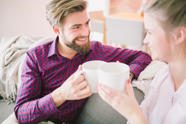 Couple with cups sitting on couch