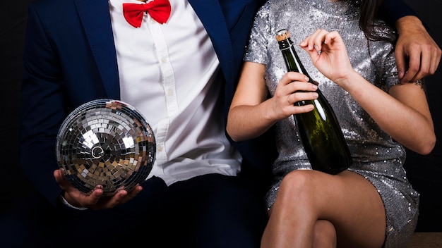 Free photo couple with disco ball and bottle of champagne