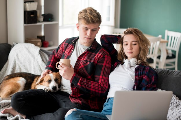 Пара с собакой смотрит на ноутбук