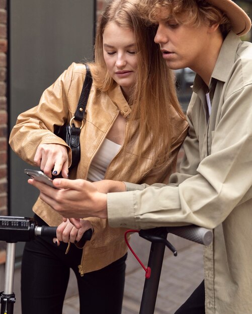 Couple with electric scooters  and smartphone outdoors