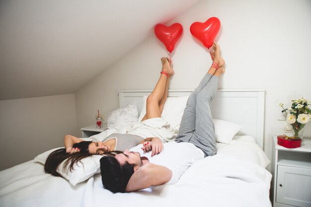 Couple with feet on the wall and holding a balloon with his foot