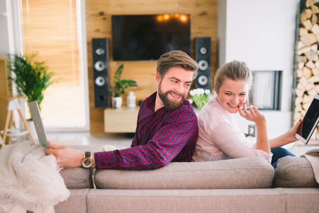 Couple with gadgets on couch
