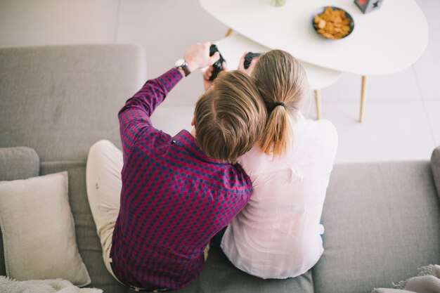 Couple with gamepads on sofa together