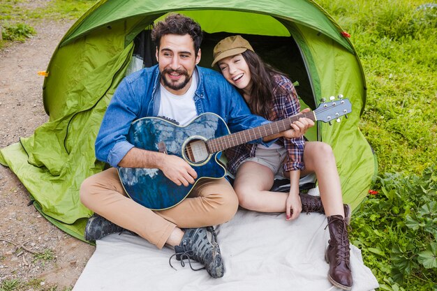 Couple with guitar near tent