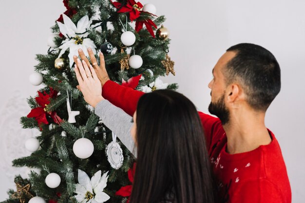 Couple with hands near Christmas tree 