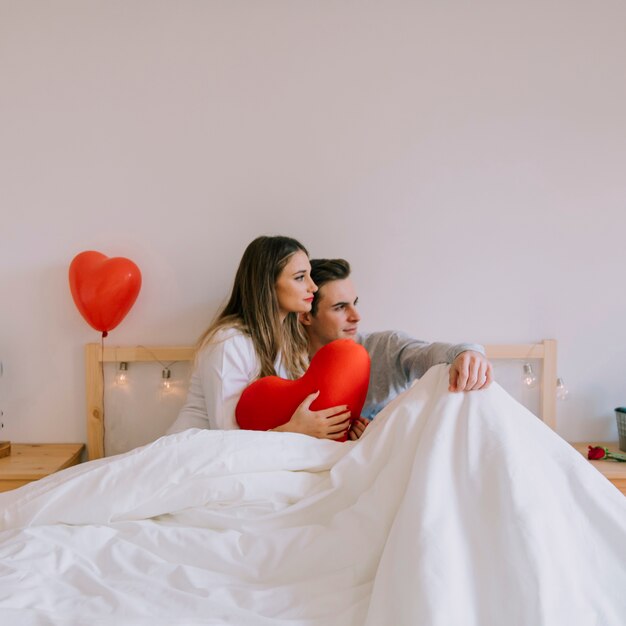 Couple with heart cushion looking away