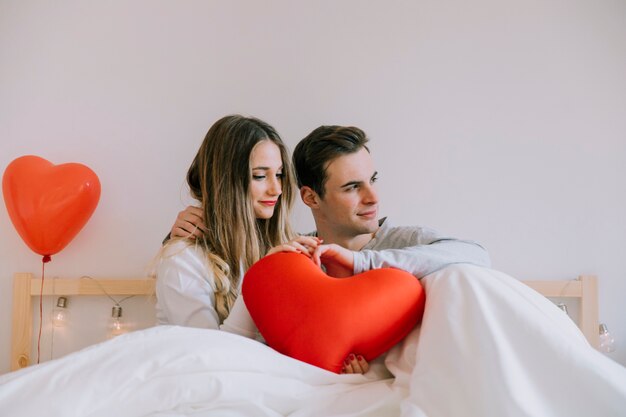 Couple with heart embracing on bed