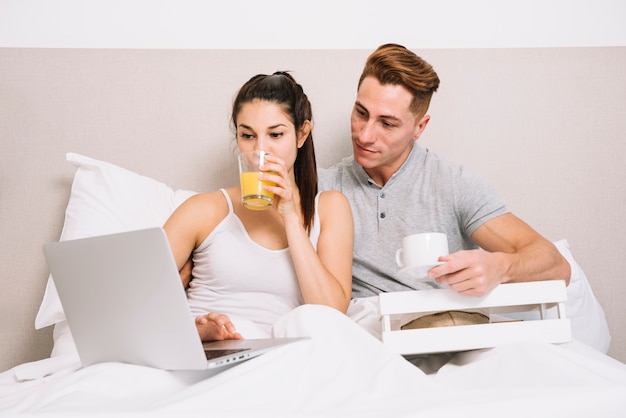 Couple with laptop having breakfast in bed