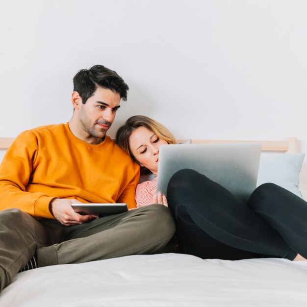 Couple with laptop lying on bed