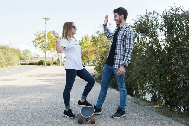 Couple with longboard high-fiving on street