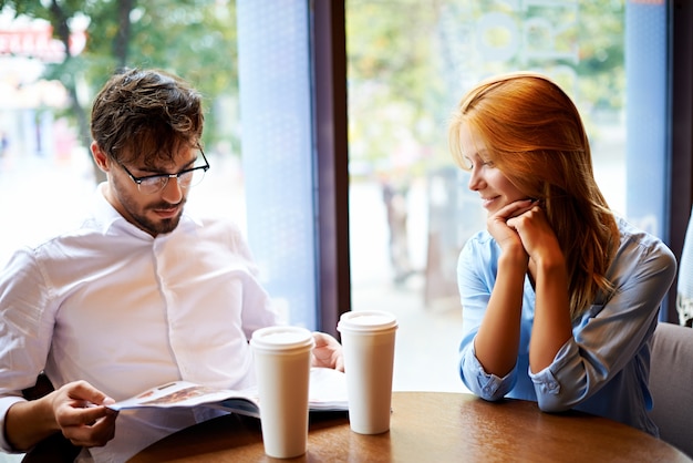 Free photo couple with magazine at coffee shop