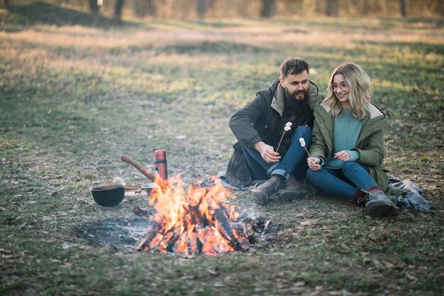 Couple with marshmallows near campfire
