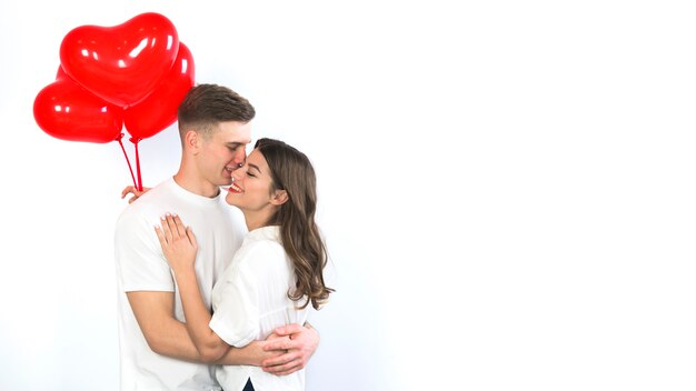 Couple with red heart balloons hugging 