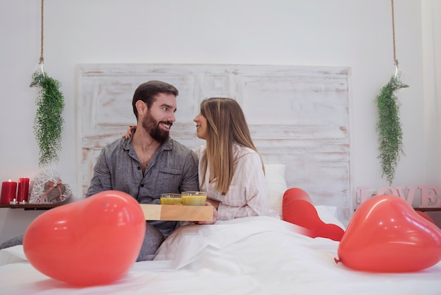 Бесплатное фото Пара с романтическим завтраком на подносе