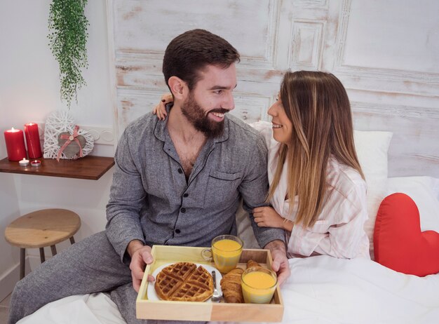 Couple with romantic breakfast on wooden tray