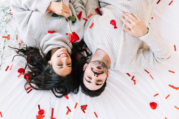 Couple with rose lying on confetti