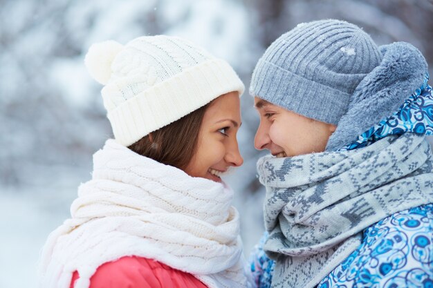 Couple with scarves and woolen hats looking at each other