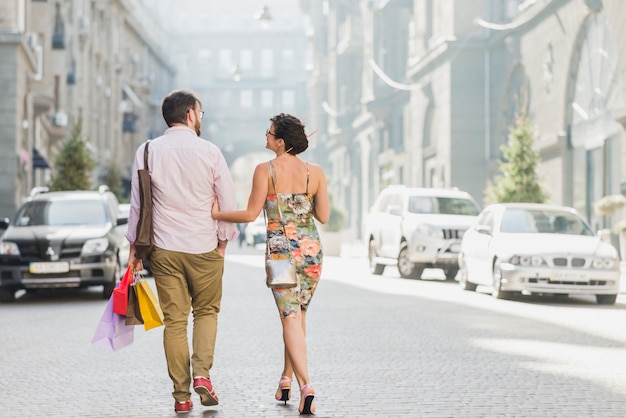 Free photo couple with shopping bags walking on street