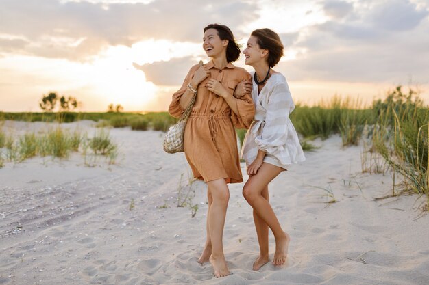 Couple with short hairstyle in linen summer clothes posing on the beach