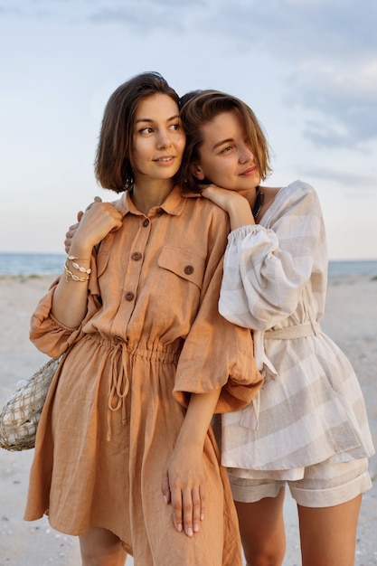 Couple with short hairstyle in linen summer clothes posing on the beach