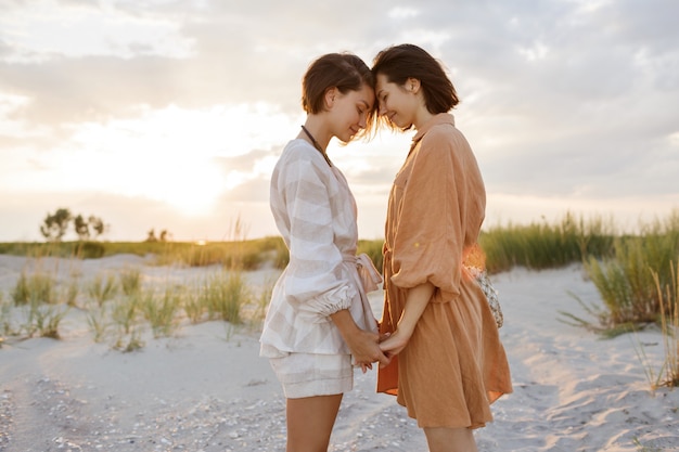 Пара с короткой прической в льняной летней одежде позирует на пляже