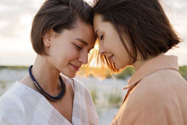 Couple with short hairstyle in linen summer clothes posing on the beach