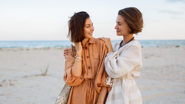 Couple with short hairstyle in linen summer clothes posing on the beach