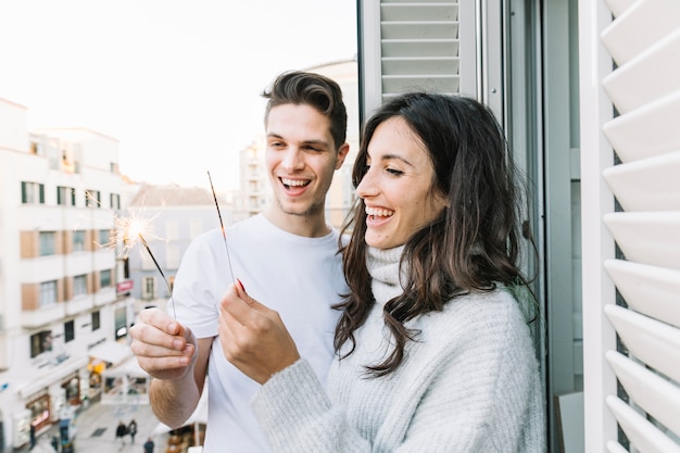 Free photo couple with sparklers on balcony