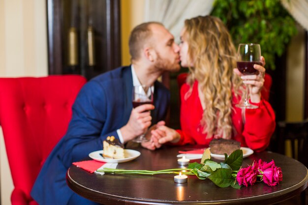 Couple with wine glasses kissing at table 