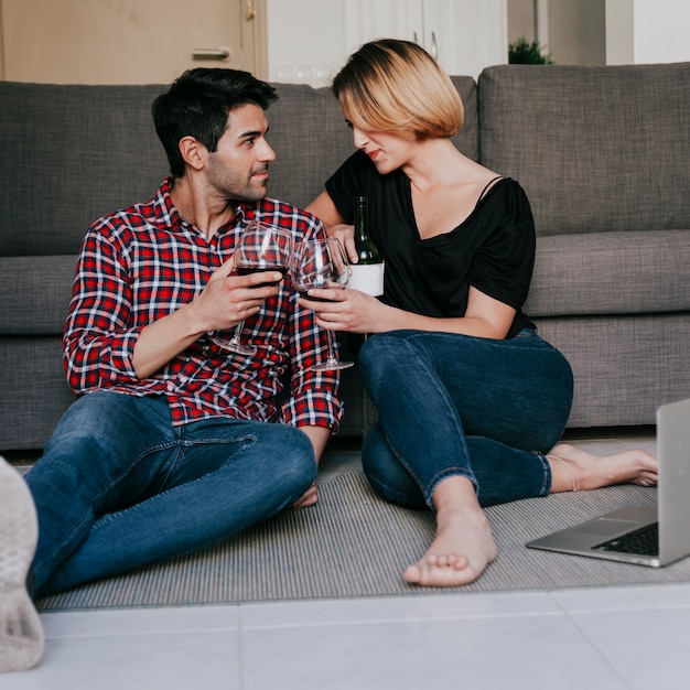 Couple with wine sitting at couch