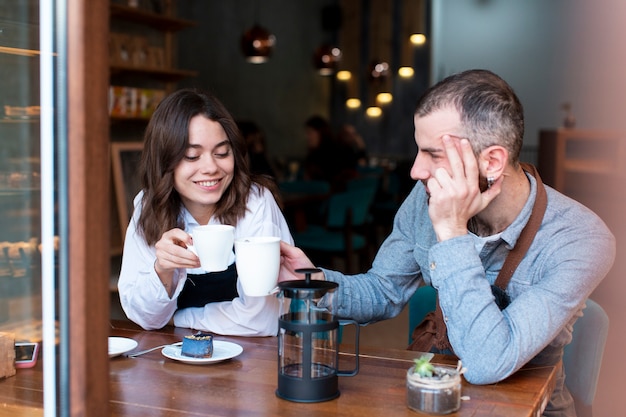 コーヒーショップで働いて、コーヒーを飲むカップル