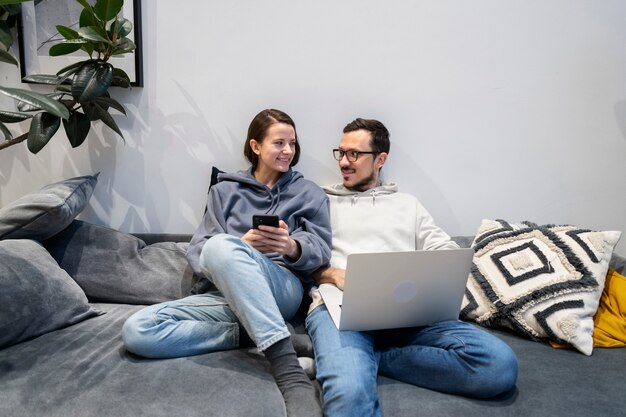 Couple working from home together on the sofa