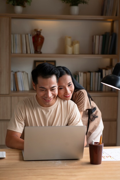 Пара работает дома на ноутбуке, будучи ласковой