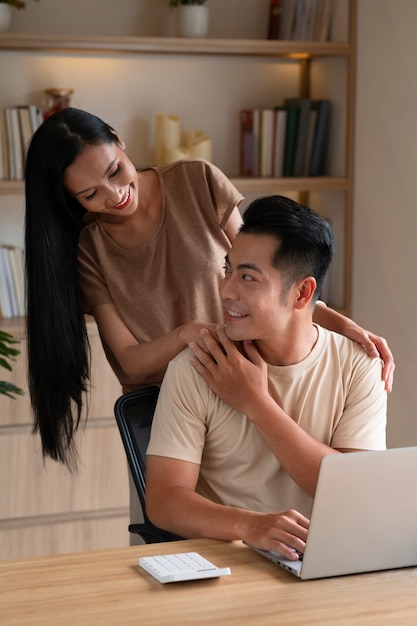 Couple working at home on laptop while being affectionate