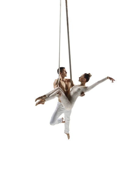 Couple of young acrobats, circus athletes isolated on white. Training perfect balanced in flight