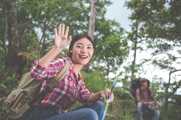 Couples drink water and see a map in the tropical forest along with backpacks in the forest. Adventure, traveling, climbing, hike.