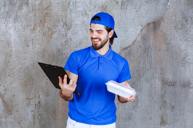 Courier in blue uniform holding a plastic takeaway box and reading the customer list.