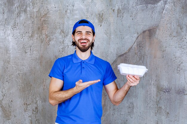 Courier in blue uniform holding a plastic takeaway box. 